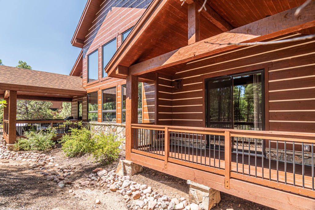 Rustic wooden cabin with deck and greenery.
