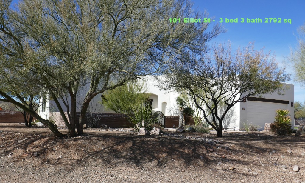 Desert home surrounded by trees and shrubs.